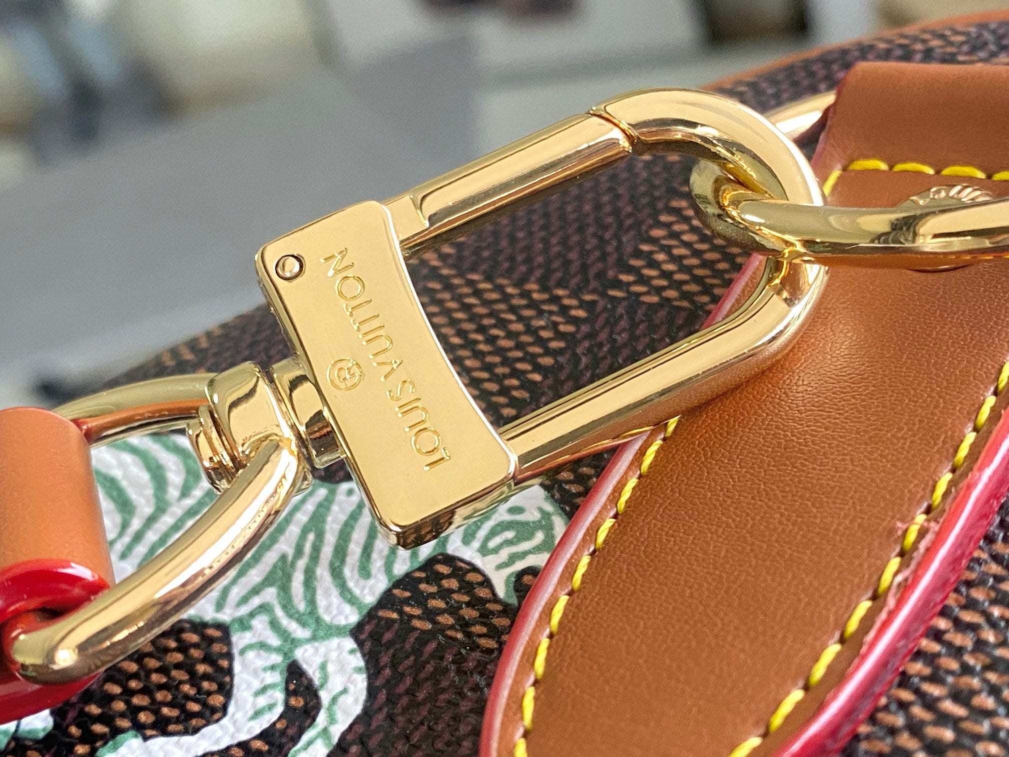 Gold tone keyring clasp on tan leather strap with Louis Vuitton engraving