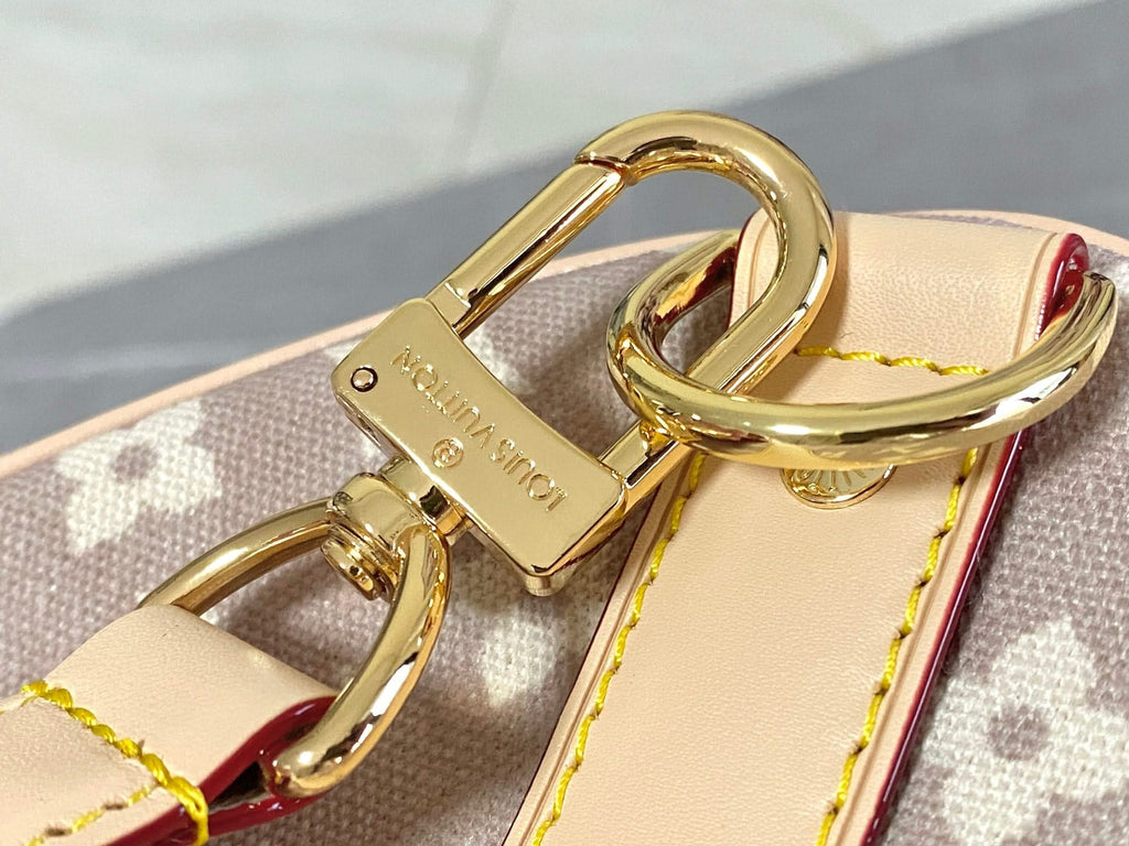 Louis Vuitton bag close-up of gold clasp and D-ring hardware on light monogram canvas.