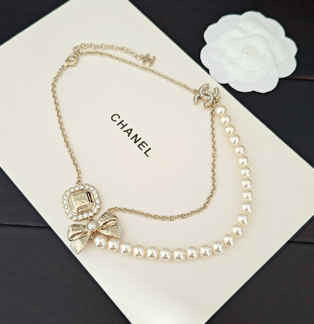 Gold-tone pearl necklace with Chanel logo on card and square bow charm