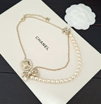 Gold-tone pearl necklace with Chanel logo on card and square bow charm