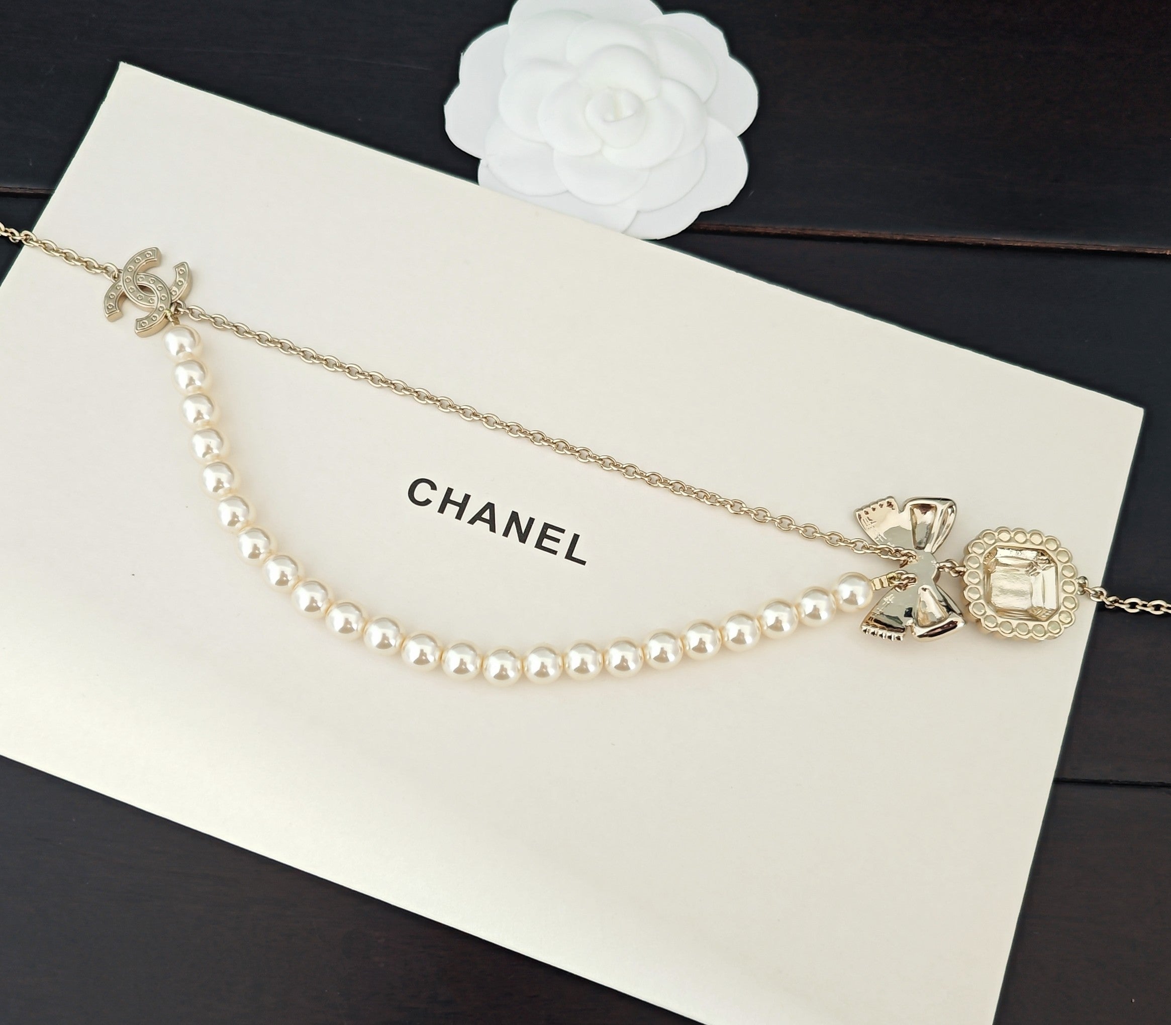Gold-tone pearl necklace with bow and charm pendants on chain