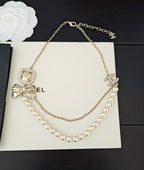 Gold-tone pearl necklace with CC-style pendant charm and dangling pearl links