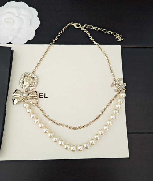 Gold-tone pearl necklace with CC-style pendant charm and dangling pearl links