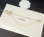 Gold-tone pearl necklace with square medallion, bow charm, and hanging pearls