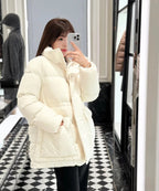 White Moncler hooded puffer jacket worn with black pants, front zipper