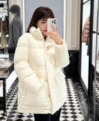 White Moncler hooded puffer jacket worn with black pants, quilted baffles