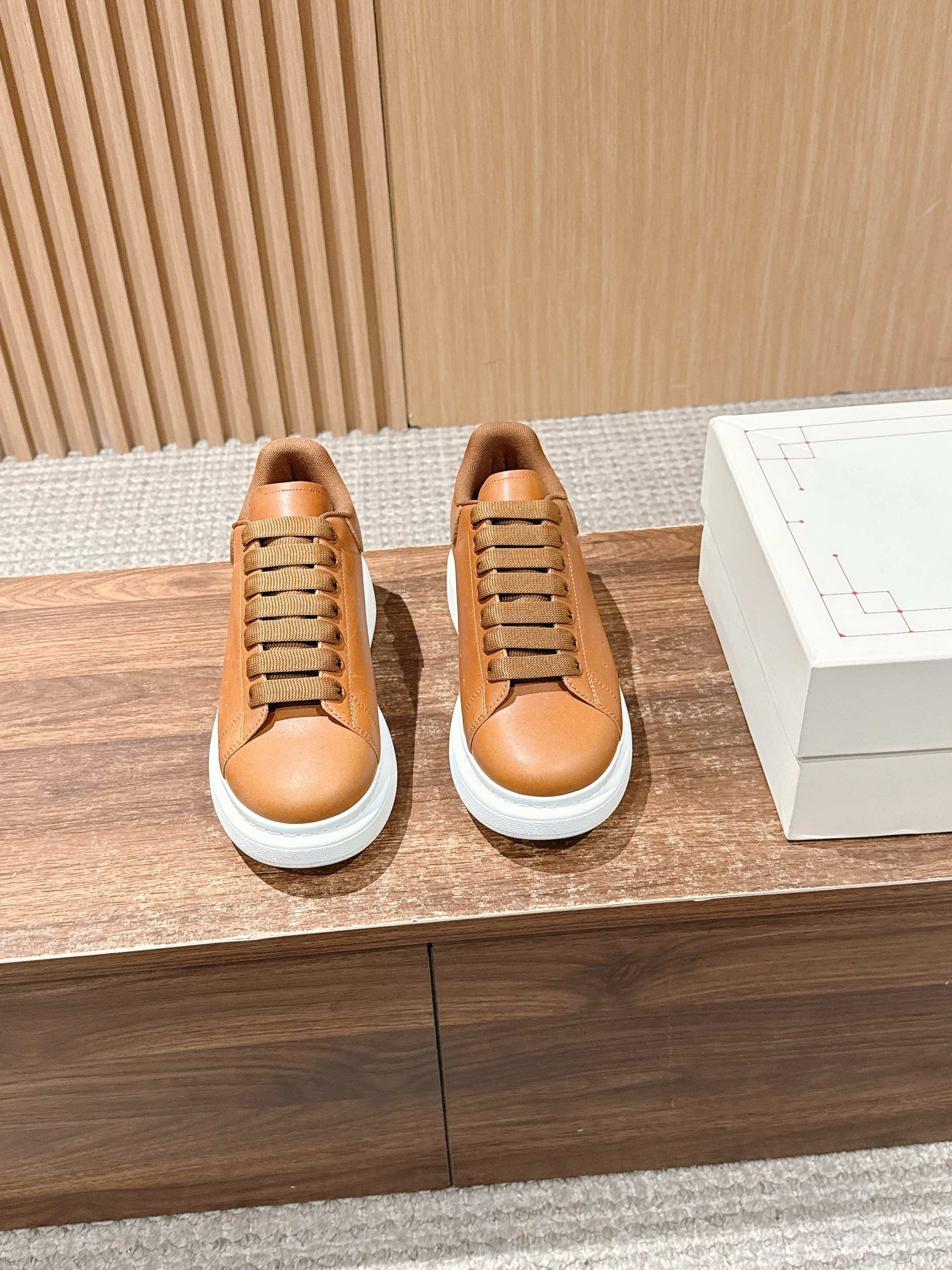 Pair of tan leather lace-up sneakers with white soles on a display