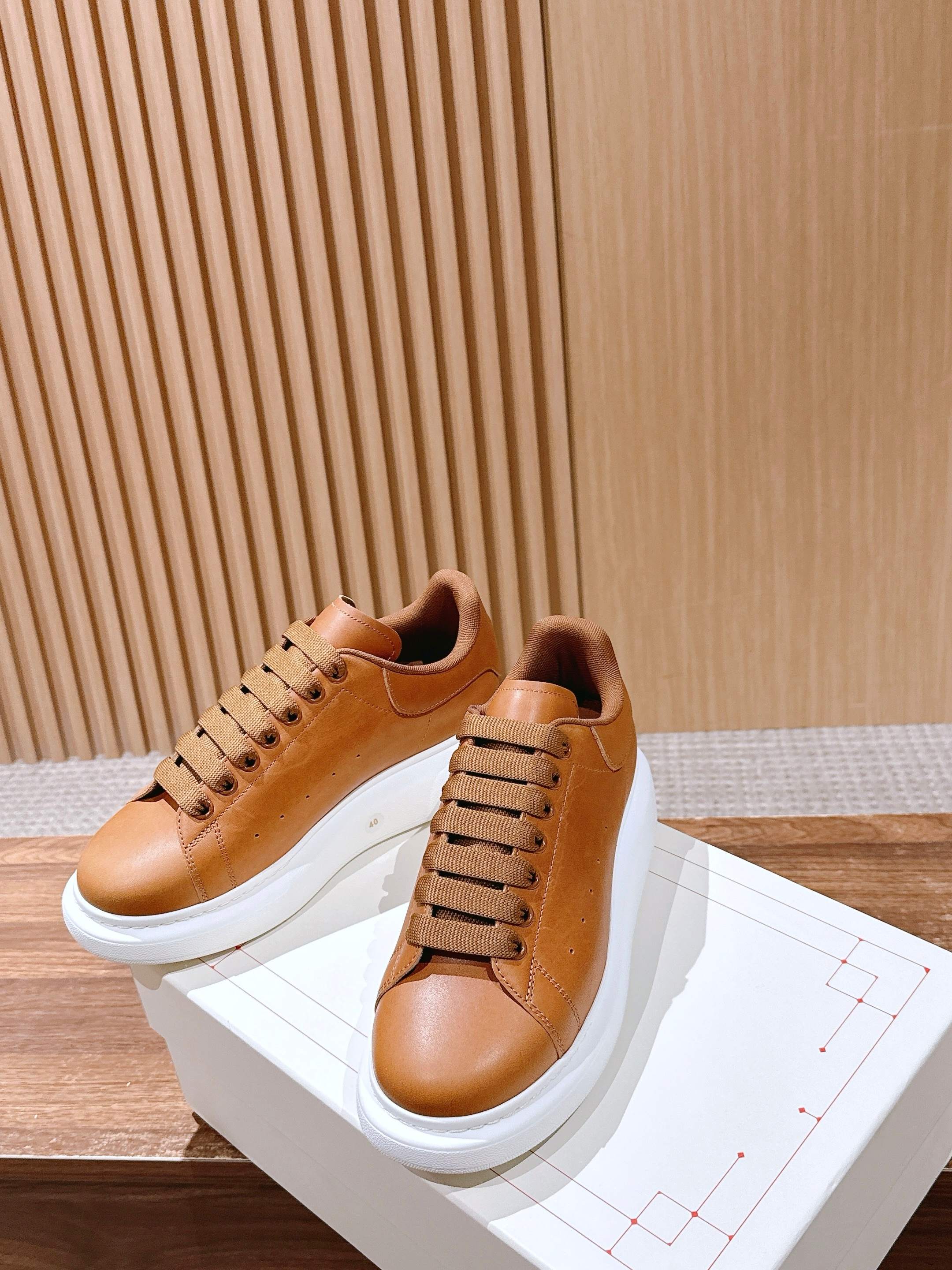 Tan leather low-top sneakers with wide laces and white rubber soles, side view