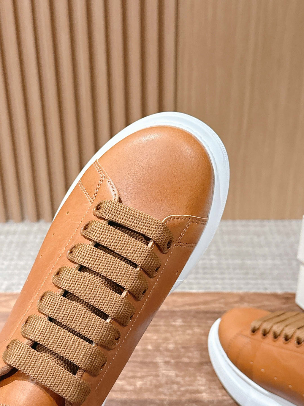 Tan leather sneaker with lace-up detail and white rubber sole edge