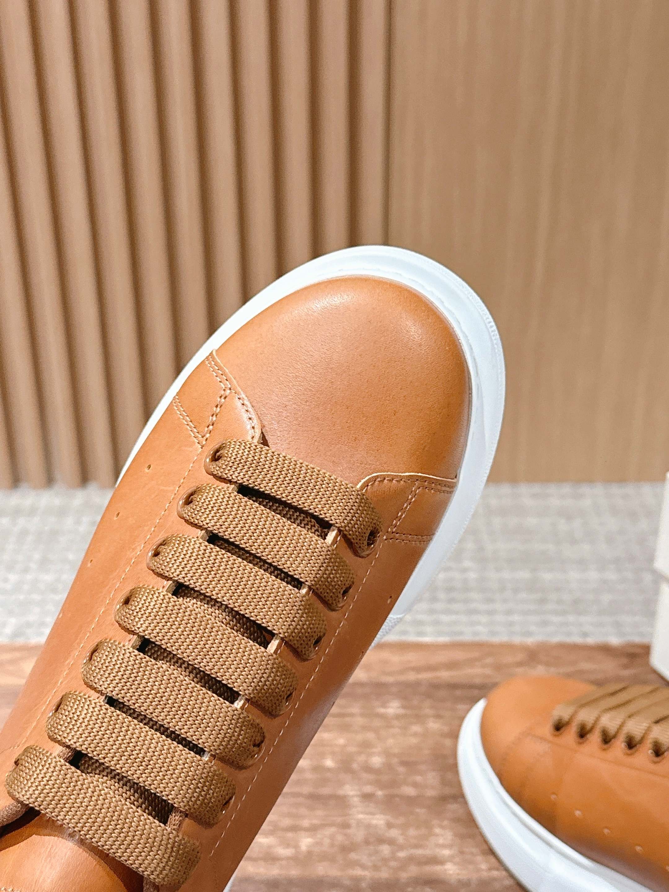 Tan leather sneaker with lace-up detail and white rubber sole edge