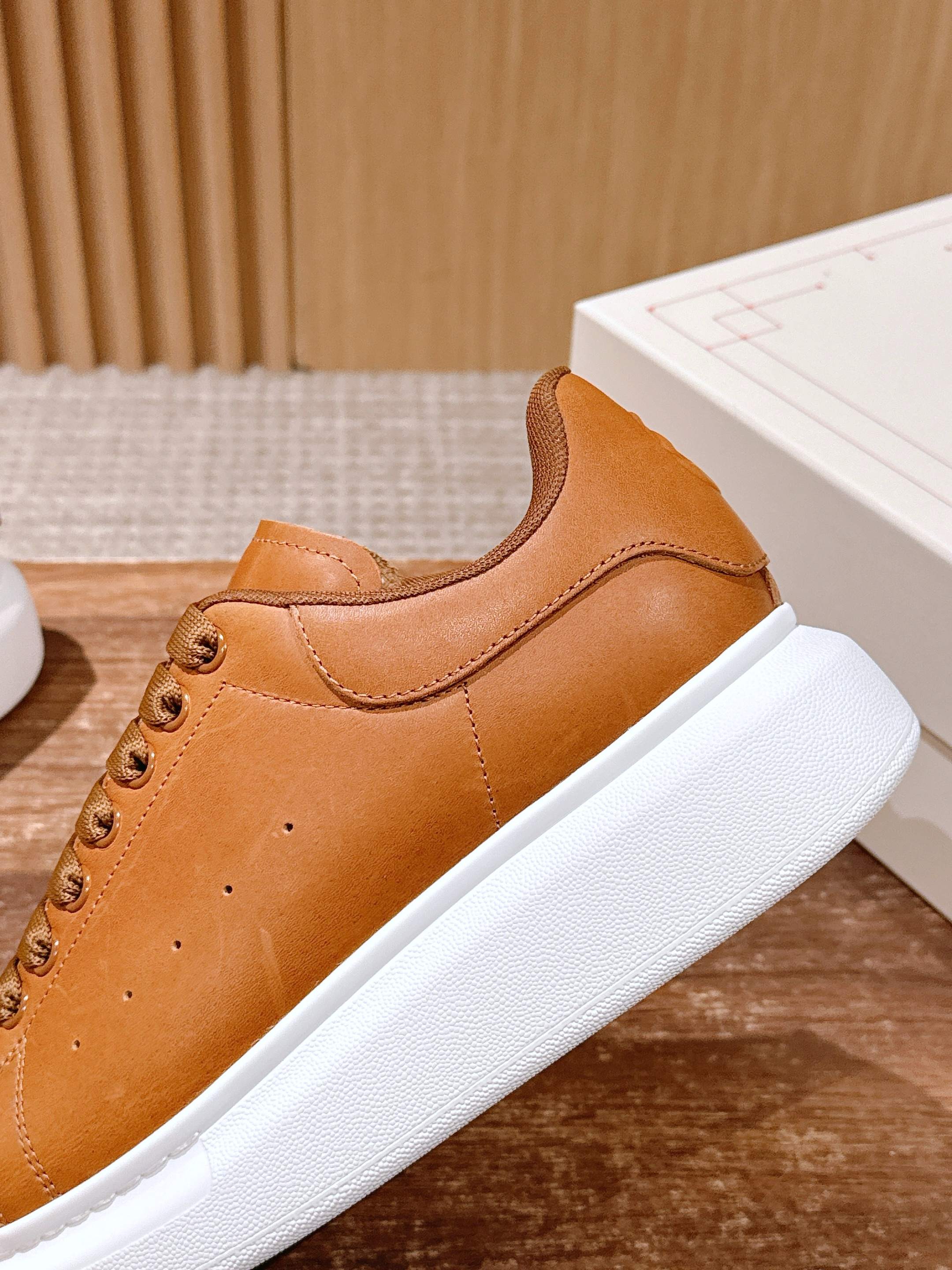 Tan leather sneakers with curved side panel, lace-up closure, white sole