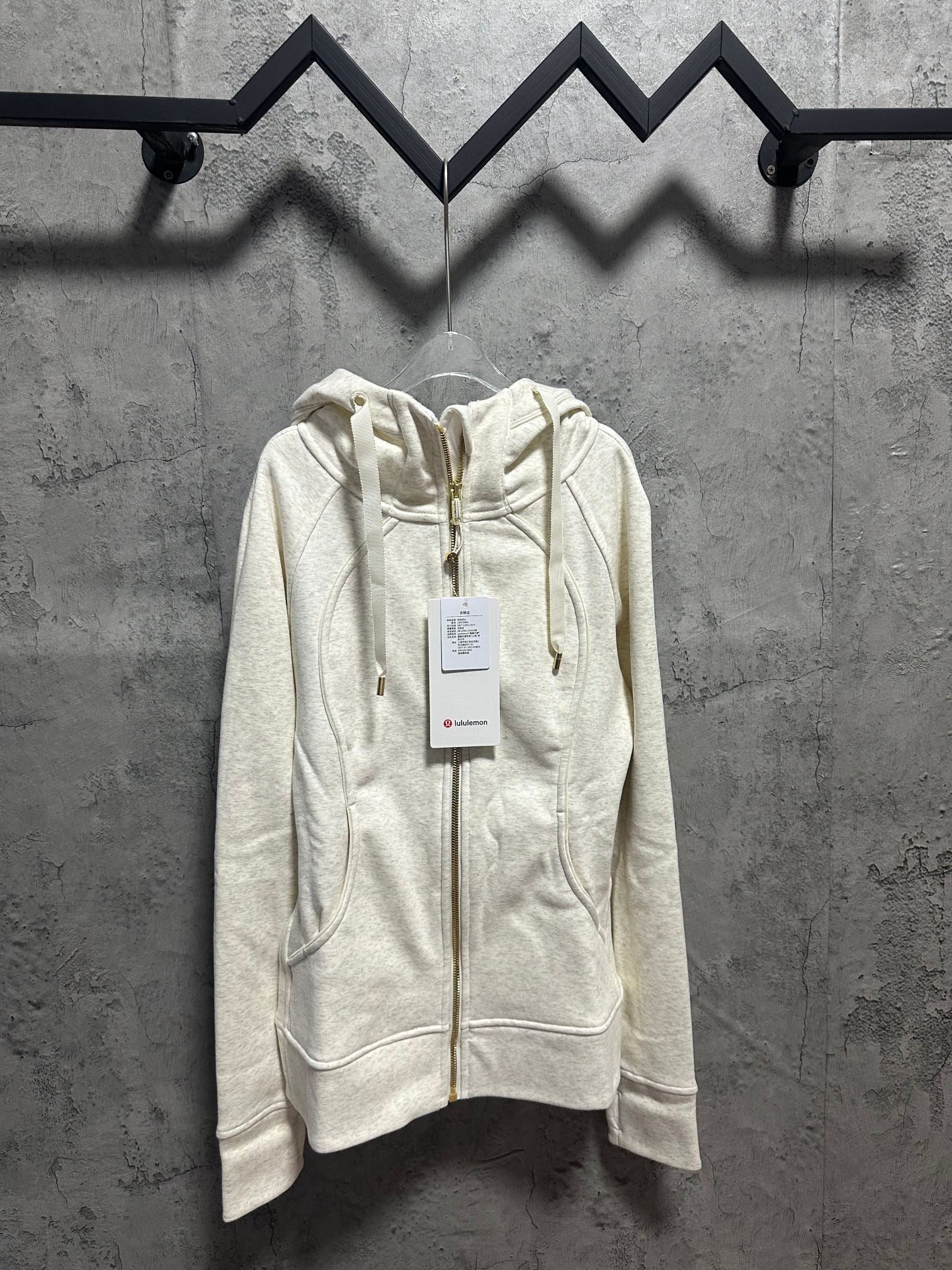 Light cream zip-up hoodie with hood, drawstring ties, and gold zipper hardware