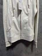 Light cream zip-up hoodie with hood, drawstring ties, and front pockets closed with zipper