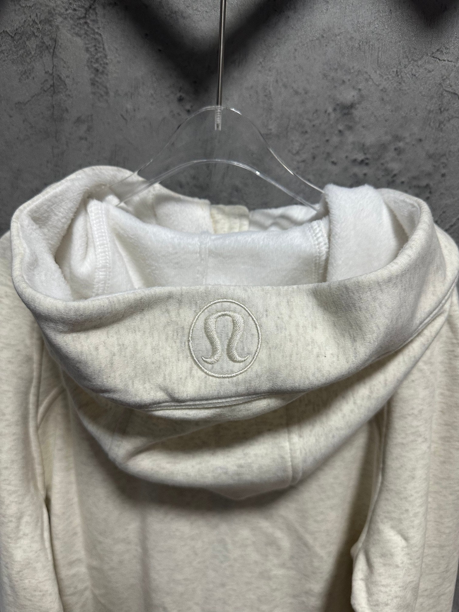 Cream hoodie with raised logo on the front of the hood