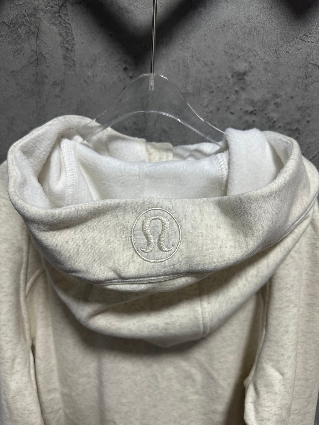 Light cream hoodie with hood and subtle embossed logo at the front neckline