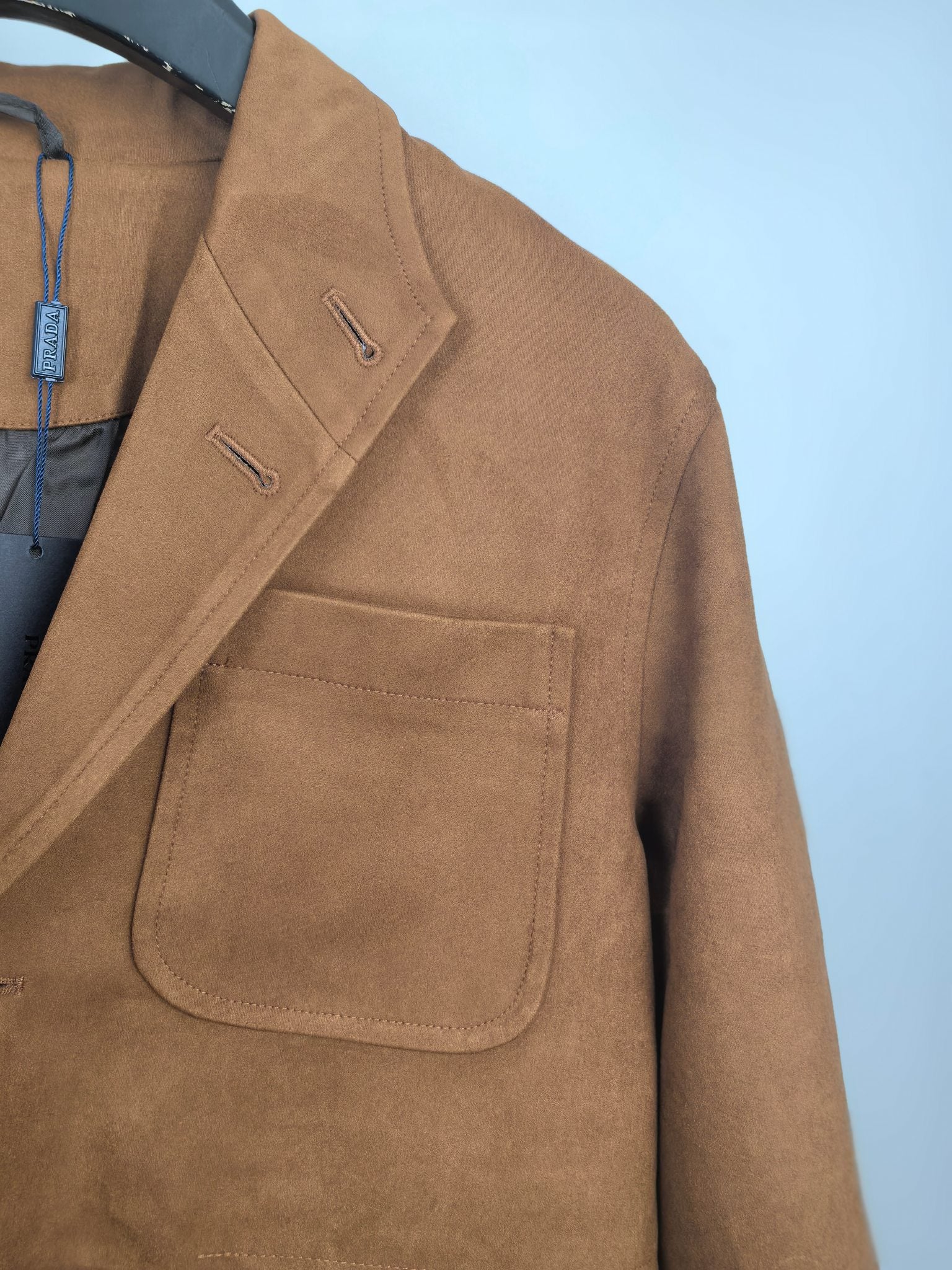 Brown suede-style jacket sleeve with flap pocket and small button detail