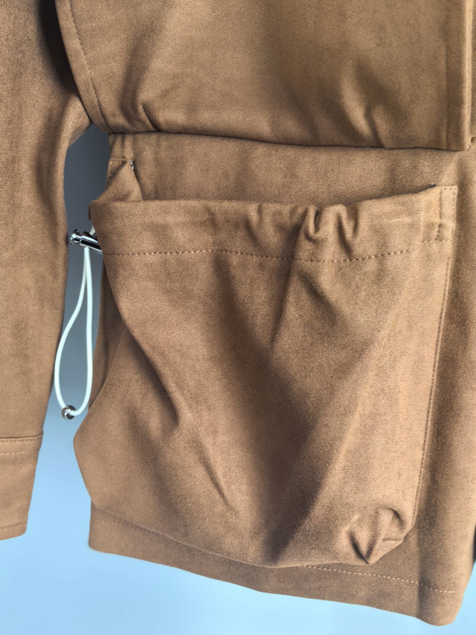 Brown suede-style jacket lower pocket with drawstring pull tab
