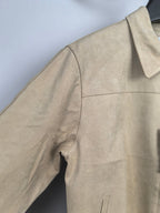 Tan jacket side panel with curved seam and open pocket detail