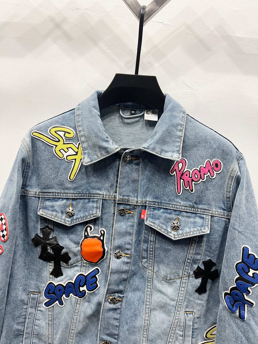 Light-wash denim jacket with embroidered patch details on chest and shoulders