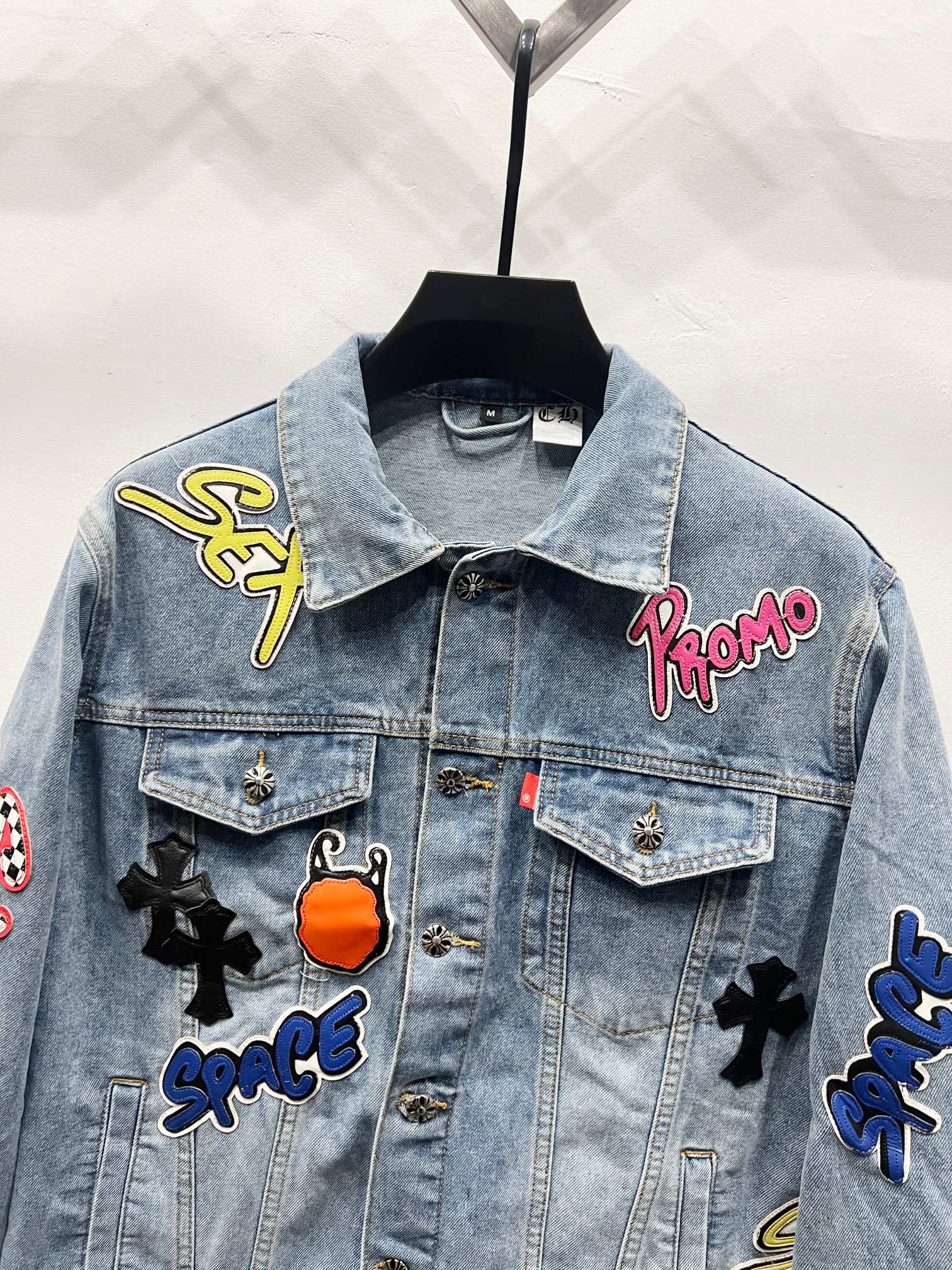 Light-wash denim jacket with embroidered patch details on chest and shoulders