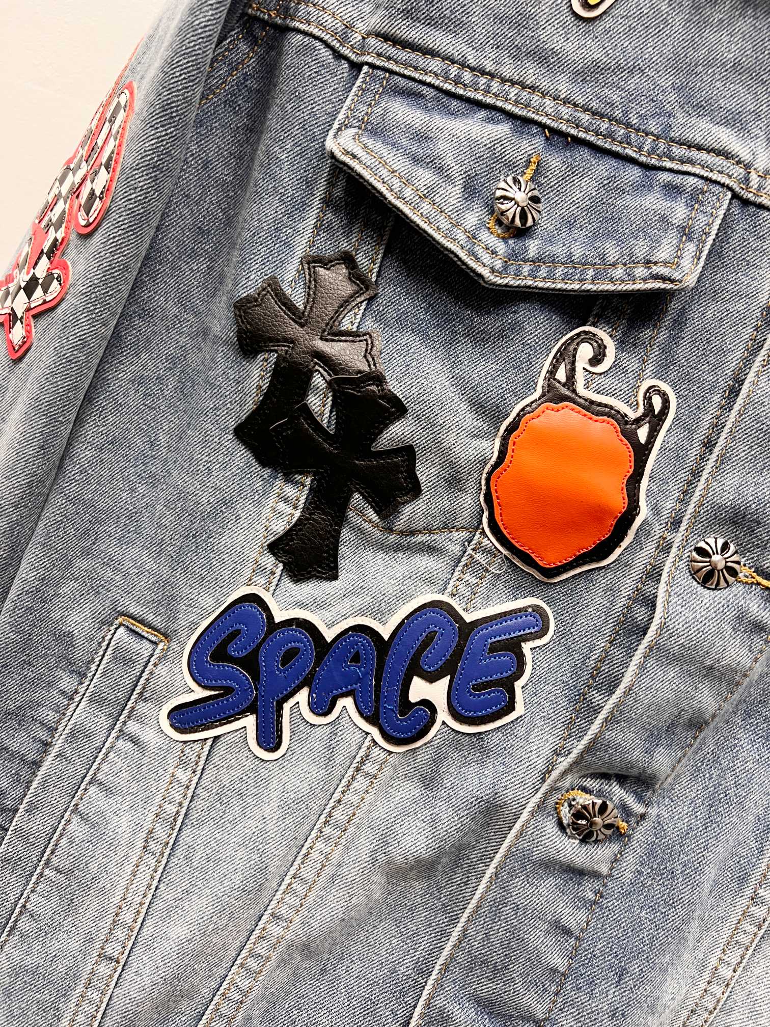 Light-wash denim jacket close-up of embroidered patches on a flap chest pocket
