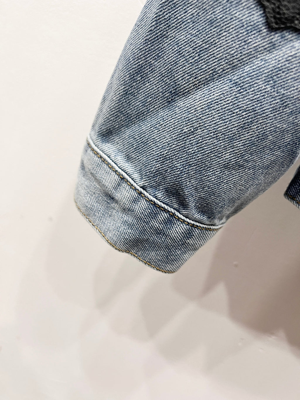 Light-wash denim jacket hem and sleeve cuff with stitched seam detail