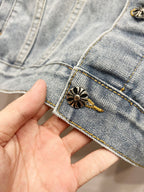 Light-wash denim jacket cuff with small gold button and embroidered flower patch