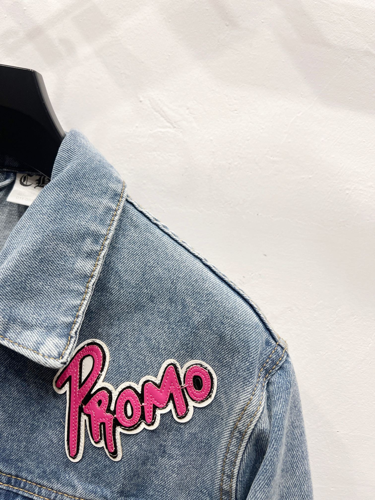 Light-wash denim jacket sleeve detail with pink 'Kromo' patch