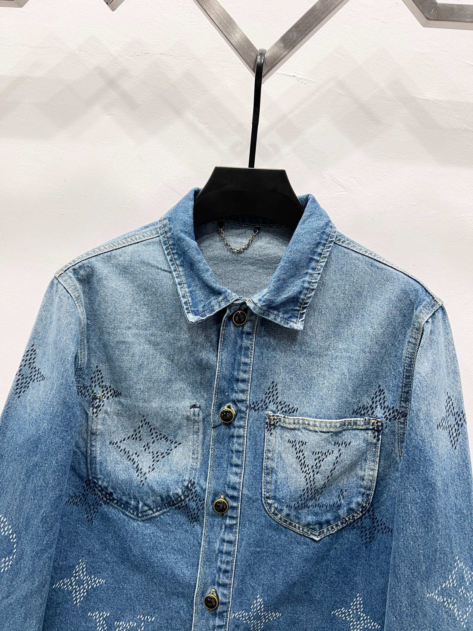 Light blue denim jacket with monogram chest panels, pointed collar and gold buttons