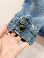 Light blue denim jacket cuff with gold-tone button and contrast stitch trim