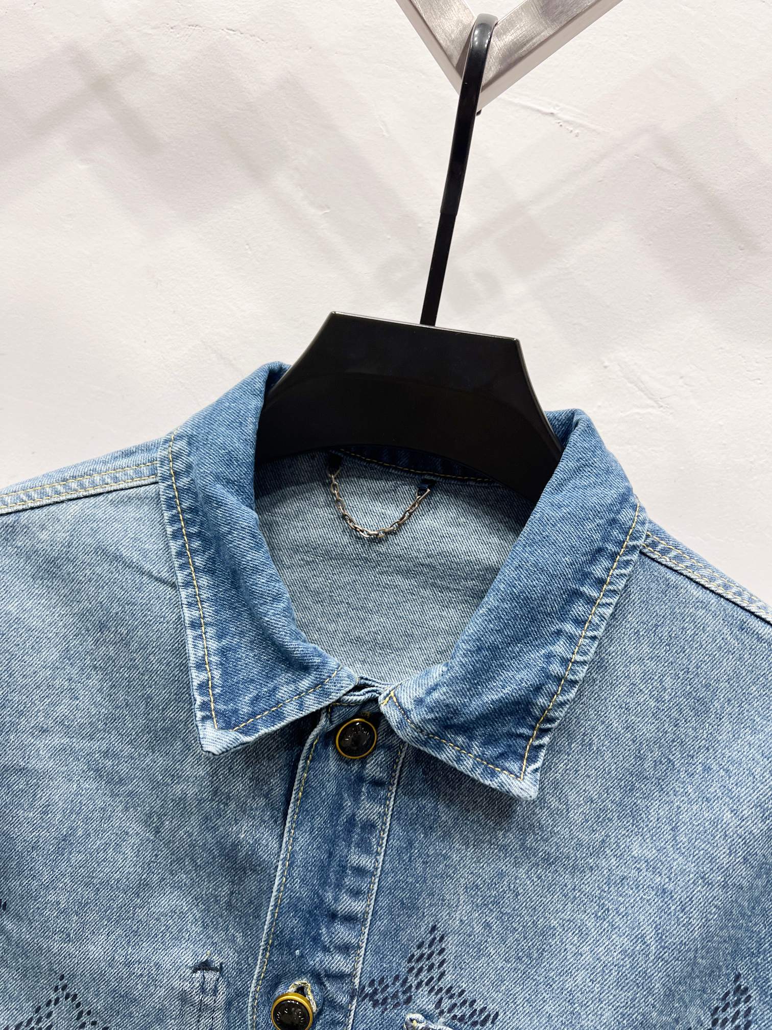 Light blue denim jacket front view with pointed collar, monogram print and button