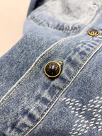 Light blue denim jacket button placket detail with gold-tone round buttons