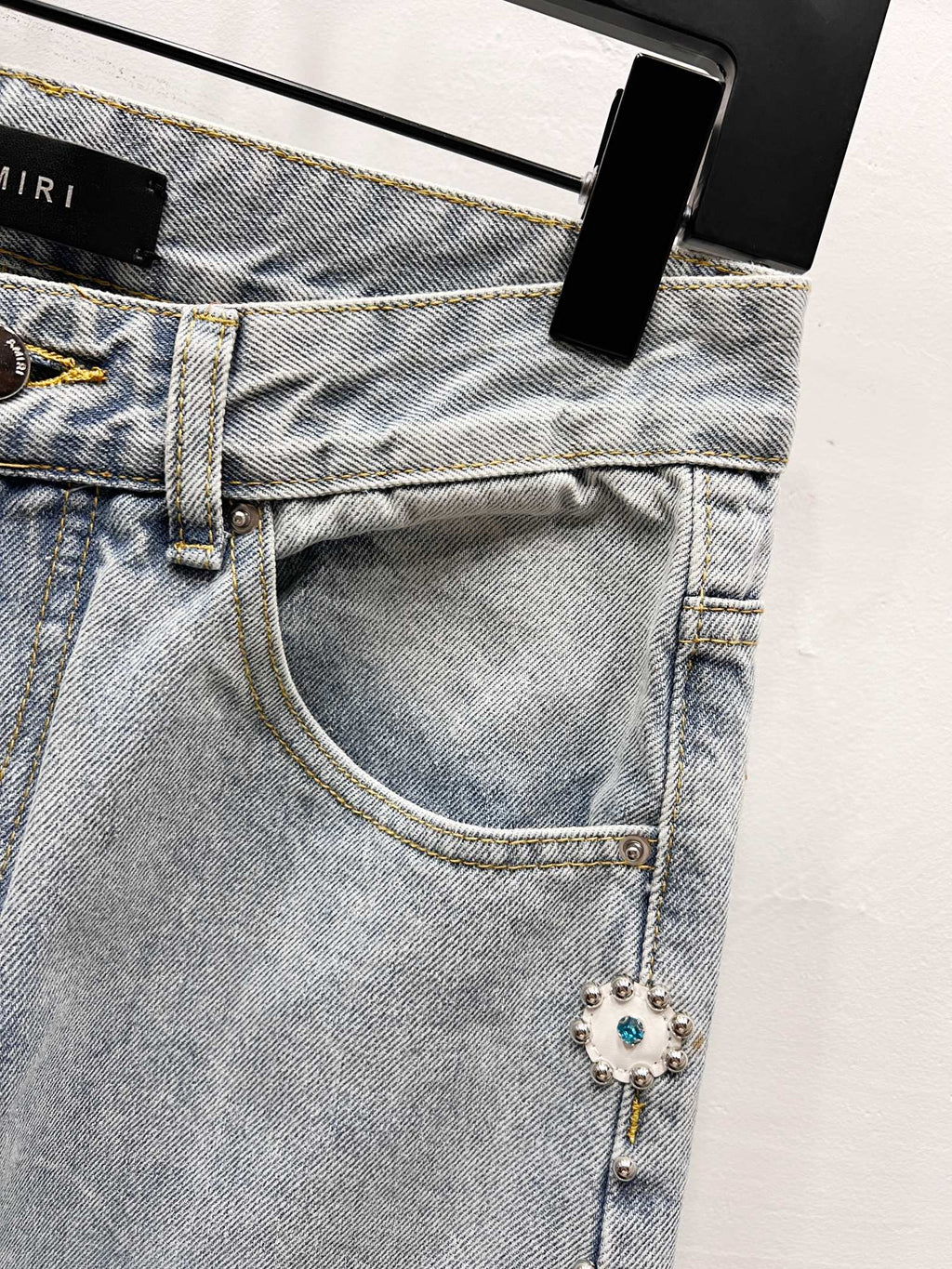 Light blue denim jeans with button waist and jeweled charm trim near pocket
