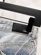 Light blue denim jeans with belt loops and black AMIKI leather-look waistband label