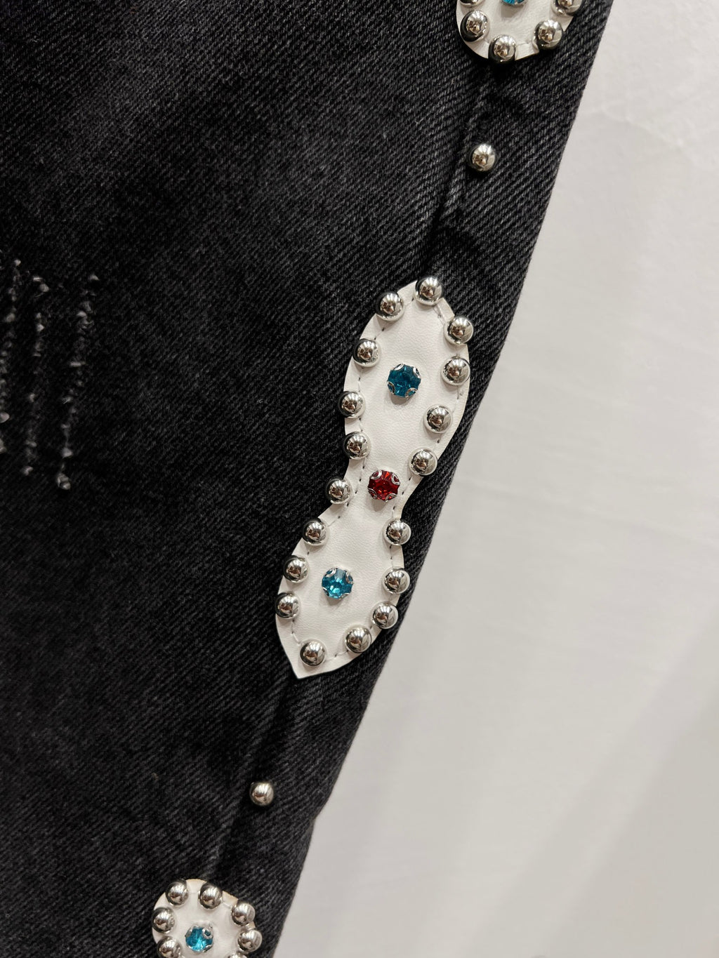 Black denim with silver-tone studs and colorful crystal accents along a side seam