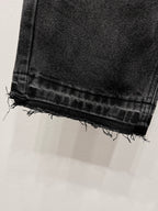 Black denim jeans with frayed raw hem at the cuff