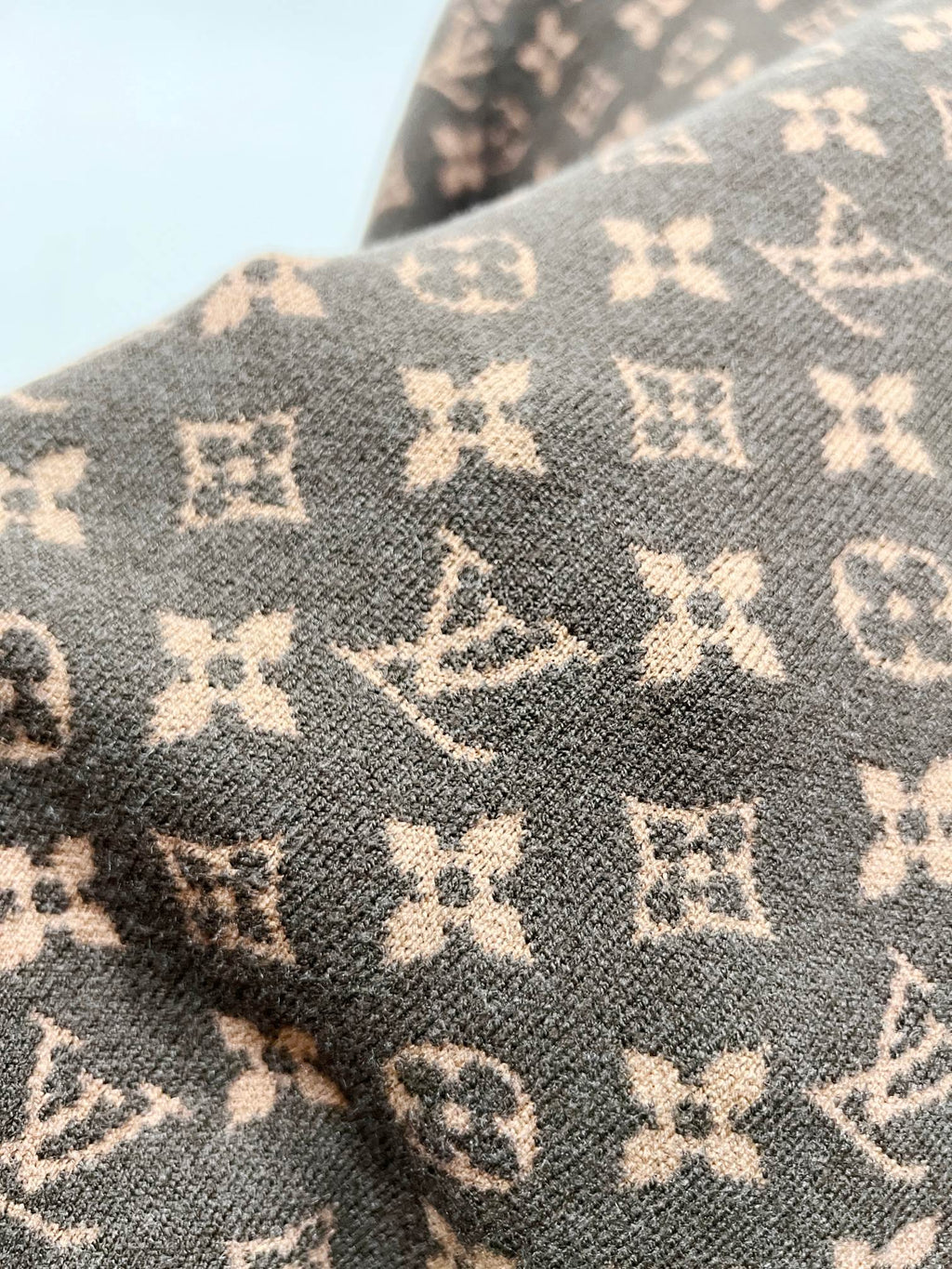 Brown knit fabric with repeating monogram motifs