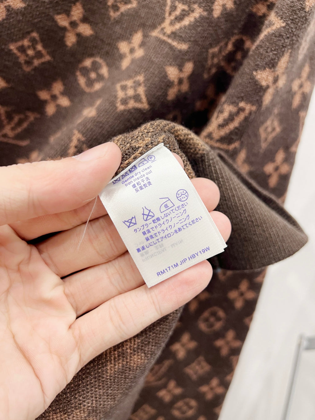 Garment care label tag on monogram sweater neckline