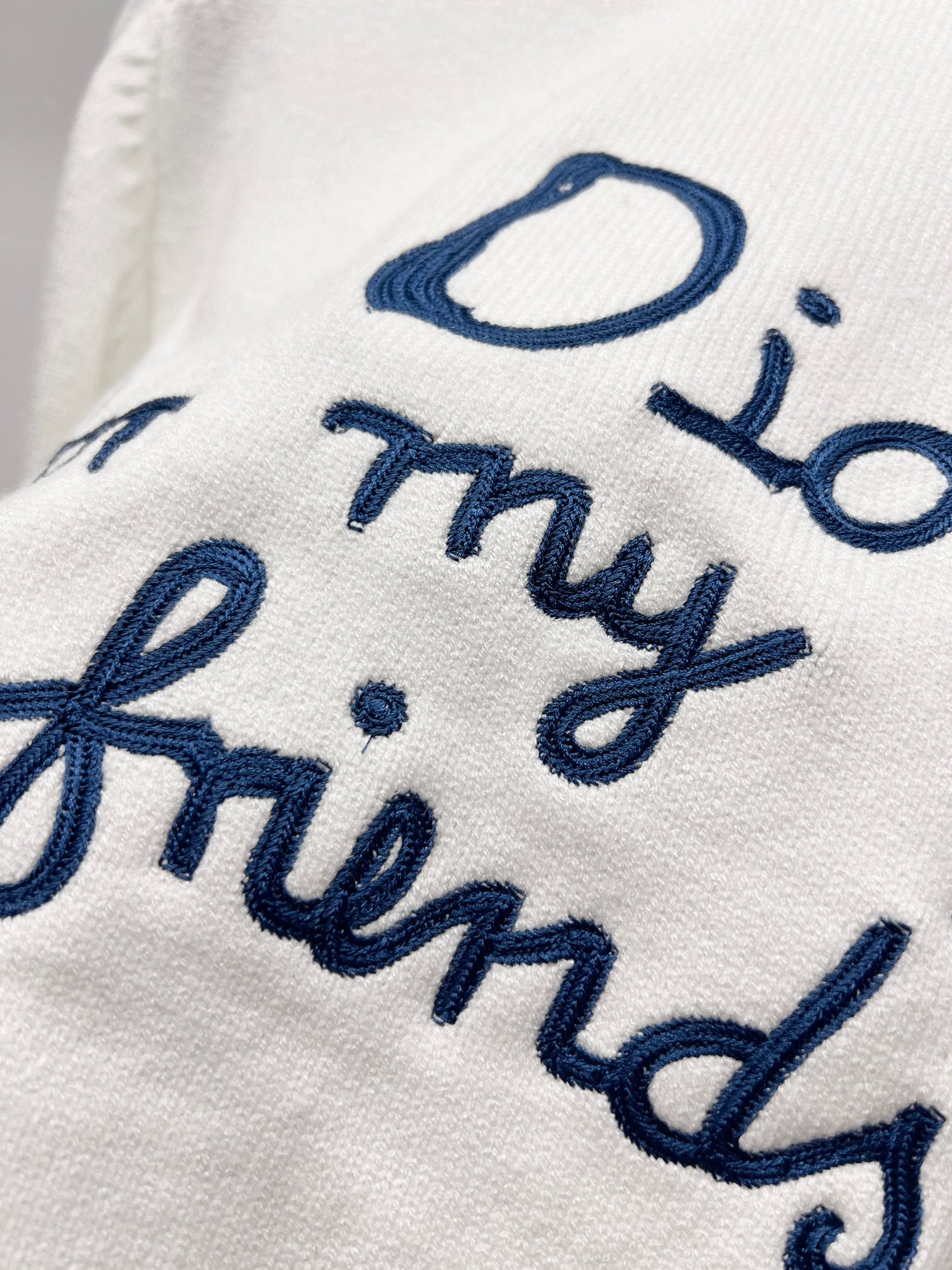 White sweatshirt with blue cursive embroidered lettering