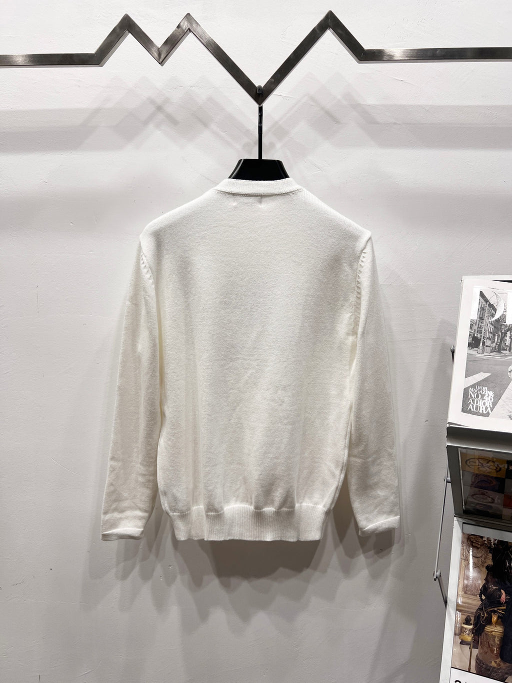 White long-sleeve crewneck sweatshirt, back view, on a display hanger