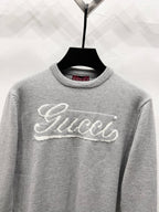 Gray knit sweater with white Gucci script logo across the chest