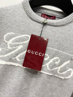 Gray sweater collar with white Gucci logo and hanging red Gucci tag