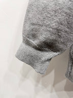 Gray knit sweater sleeve cuff and curved hem detail
