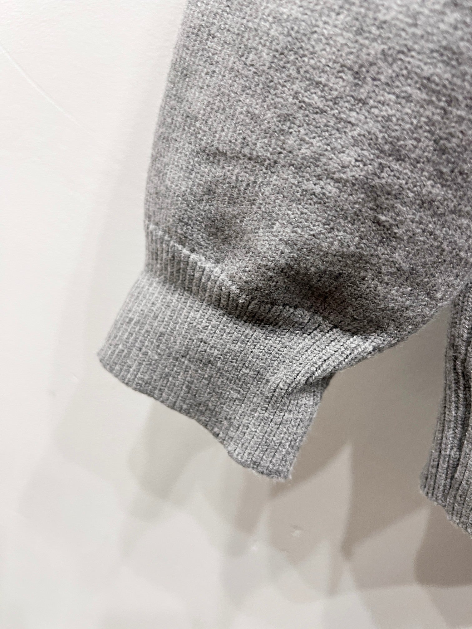 Gray knit sweater sleeve cuff and curved hem detail