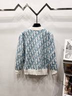 Logo knit sweater on hanger, light blue repeating pattern with white ribbed cuffs and hem