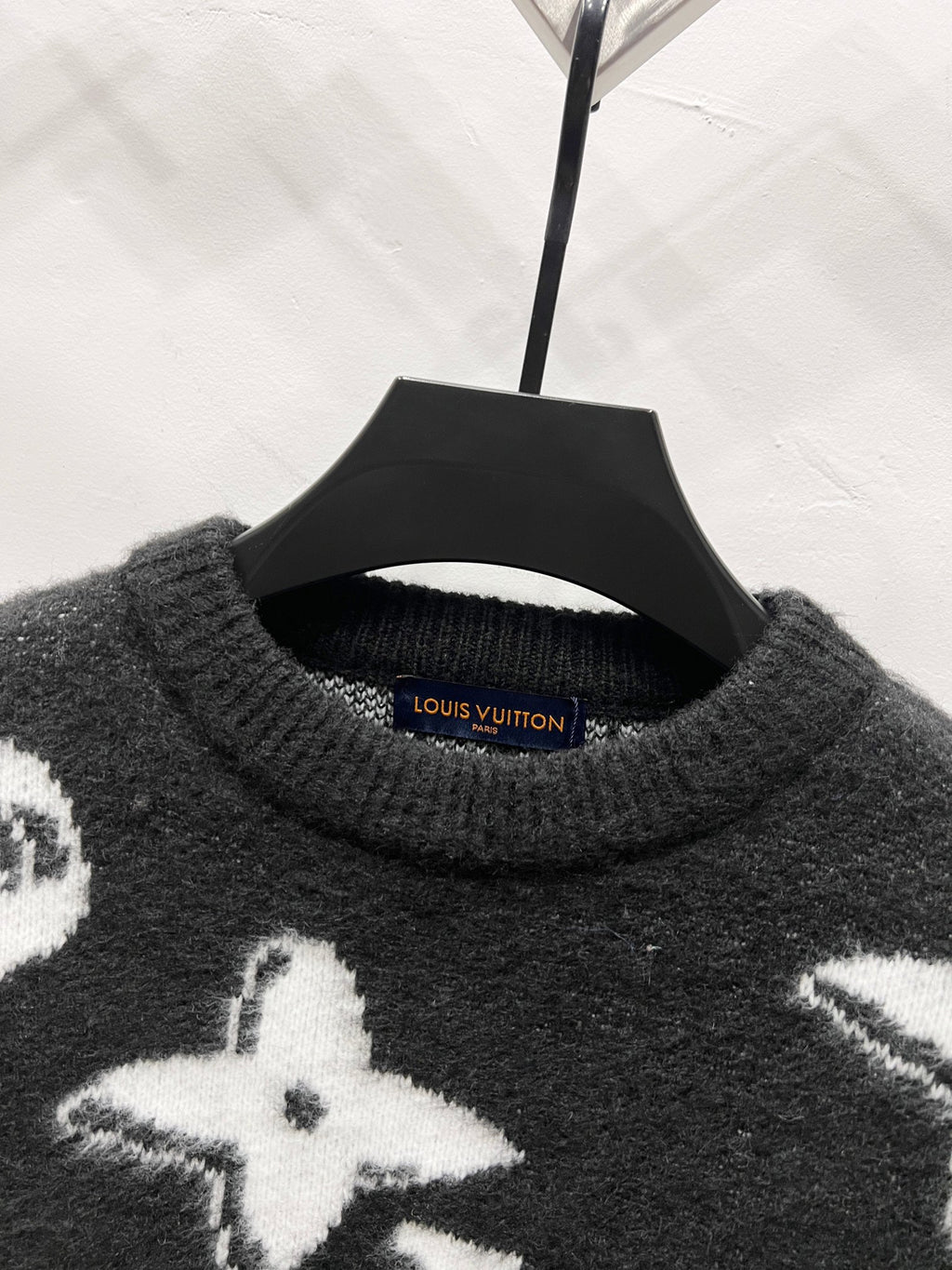 Black crewneck knit sweater with white star graphic at the chest