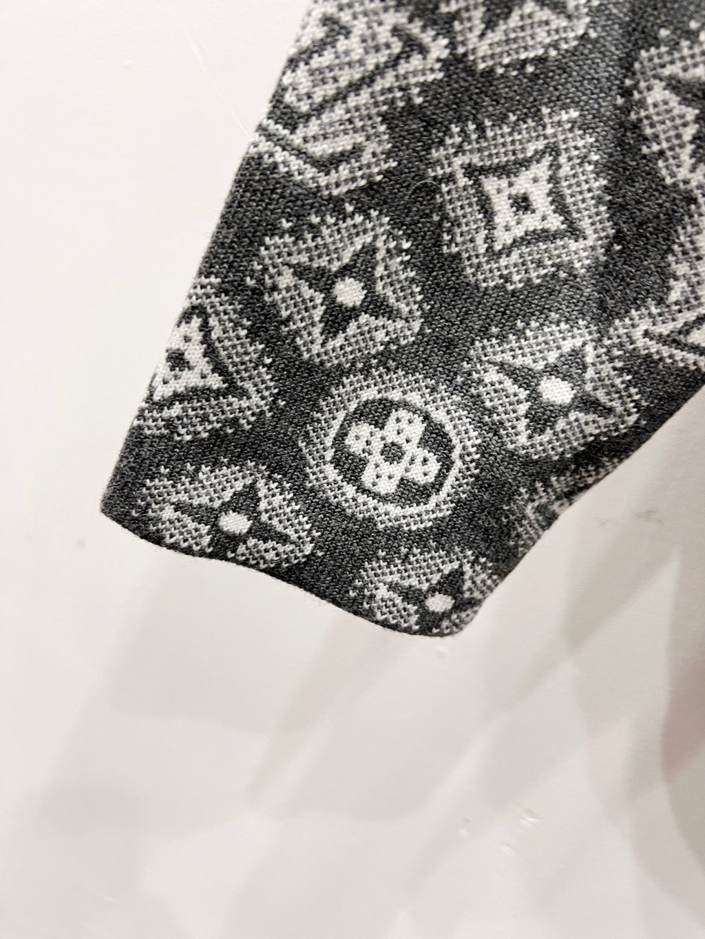 Patterned knit hoodie panel in dark gray with monogram motifs, angled view