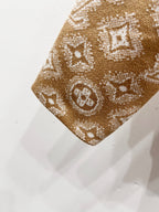 Tan monogram knit fabric swatch with repeating symbols