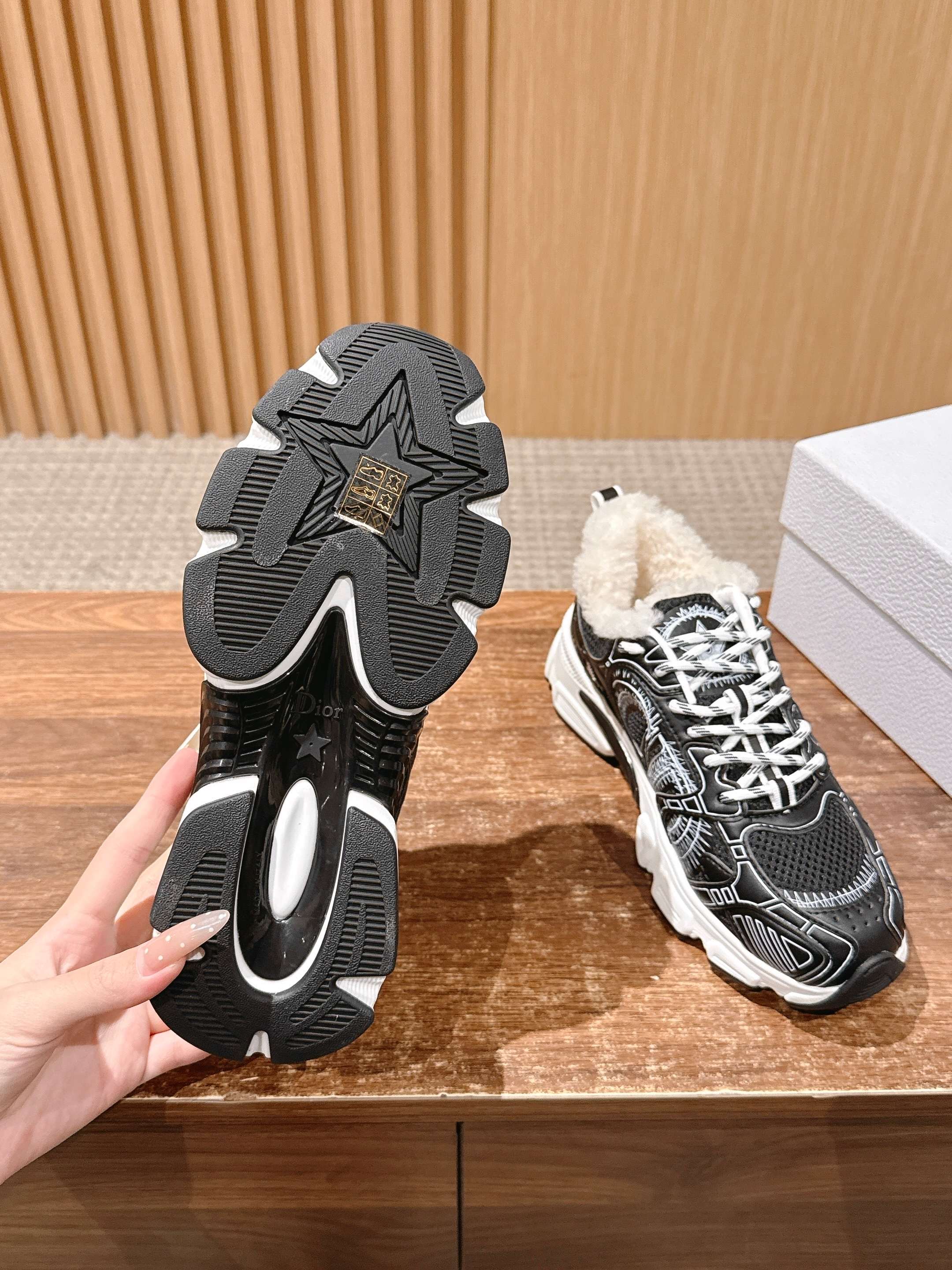 Unisex sneakers outsole view with star-shaped tread, black uppers, faux fur trim