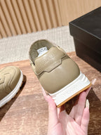 Prada unisex light beige sneaker held by the heel, showing molded logo tab.